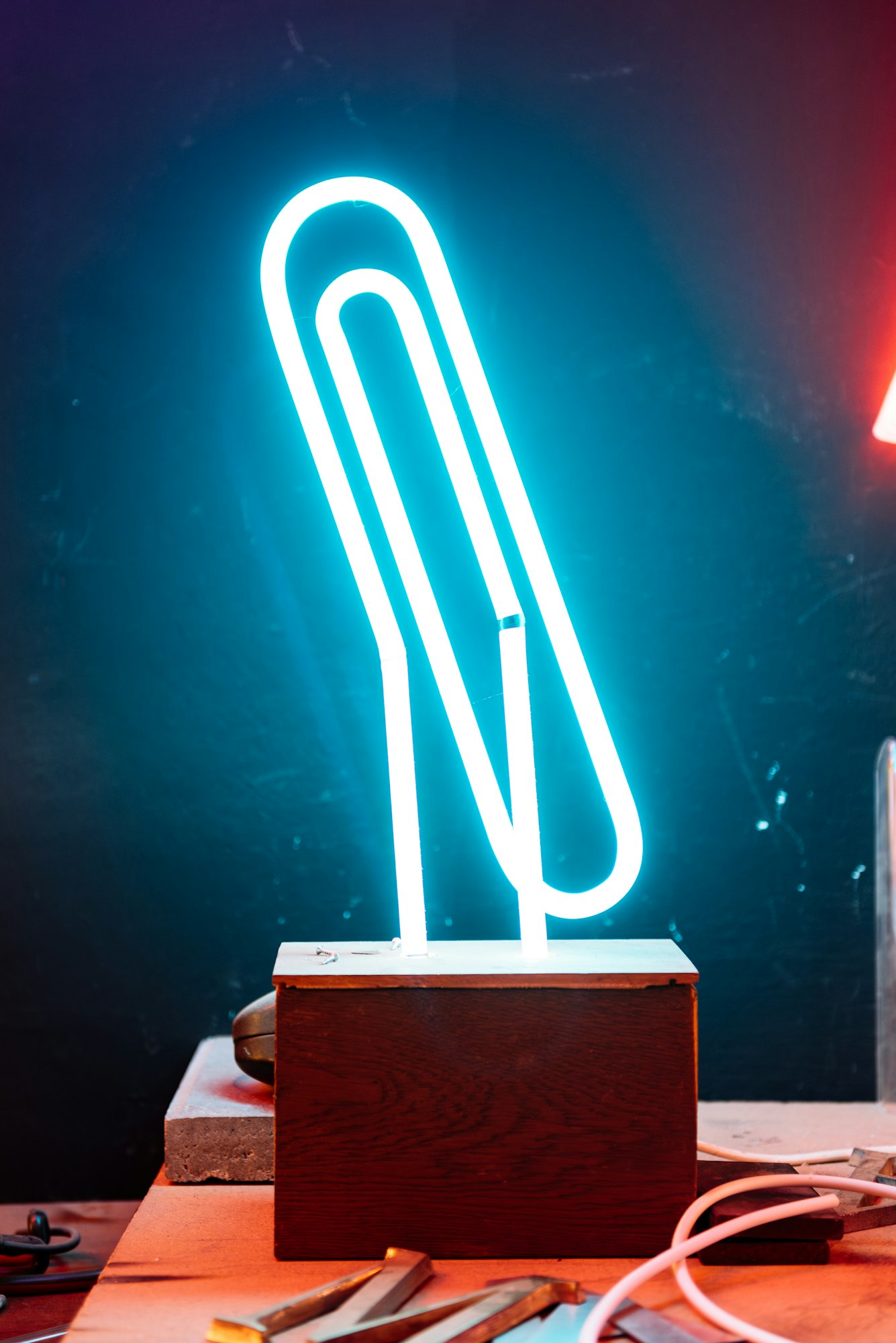 Blue Neon Paper Clip Light On A Wooden Base