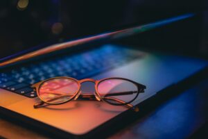 Close up of laptop keyboard colorful neon illumination and eyeglasses.